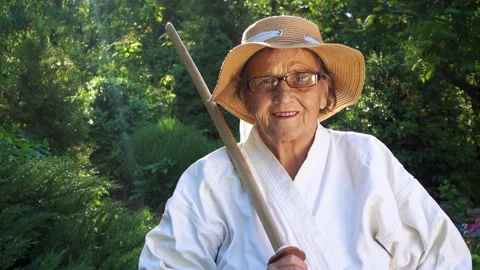 Portrait of an old lady training with a katana in the garden. Camera movement. Stock Footage 310332905