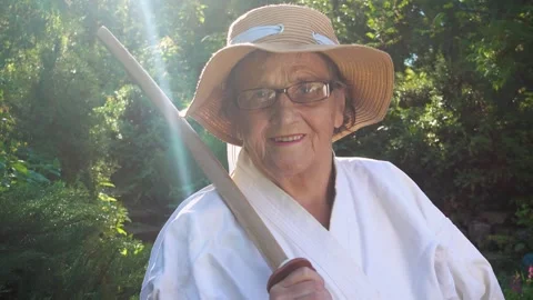 Portrait of an old lady training with a katana in the garden. Camera movement. Stock Footage 310332937
