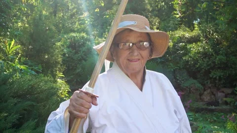 Portrait of an old lady training with a katana in the garden. Camera movement. Stock Footage 310332941