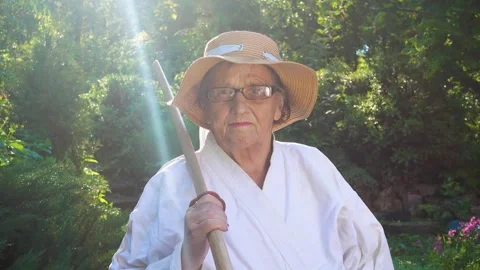 Portrait of an old lady training with a katana in the garden. Camera movement. Stock Footage 310332942