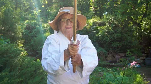 Portrait of an old lady training with a katana in the garden. Camera movement. Stock Footage 310332944