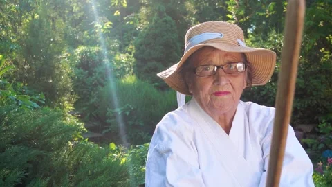 Portrait of an old lady training with a katana in the garden. Camera movement. Stock Footage 310332947