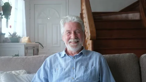 Portrait of old man smiling and looking at the camera sitting on the sofa from h Vídeo Stock 151323053
