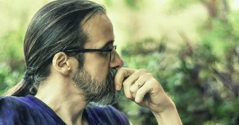 Portrait of one mid adult man with beard, glasses and long hair in a ponytail Stock Photos