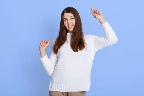 Portrait of optimistic dark haired young woman poses with hands up, dances .. Stock Photos
