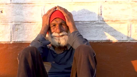 Portrait or Mid shot of an old aged man sitting on the floor at sunset, holdi Video stock 168133433