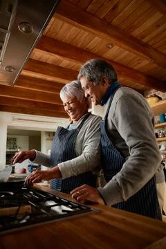 Portrait orientation of Elderly multi-ethnic couple happily cooking breakfast Stock Photos