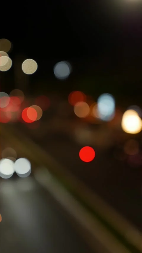 Portrait oriented view of blurred vehicle headlights and street lamps forming Stock Footage 336236096