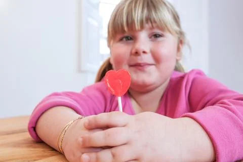 Portrait of overweight girl holding heart shape lollipop Stock Photos