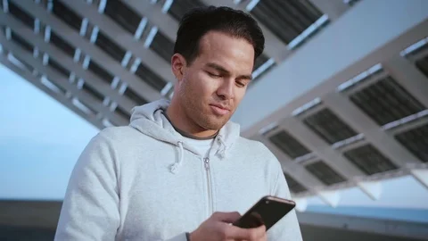 Portrait of pensive Hispanic guy looking serious, while using app on smart phone Video stock 105754653