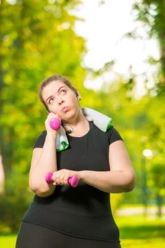 Portrait of a pensive plus size model engaged with dumbbells during a workout Stock Photos