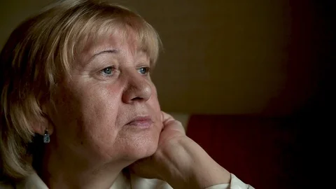 Portrait Pensive sad lonely Elderly Mature Woman looking out window Stock Footage 100971403
