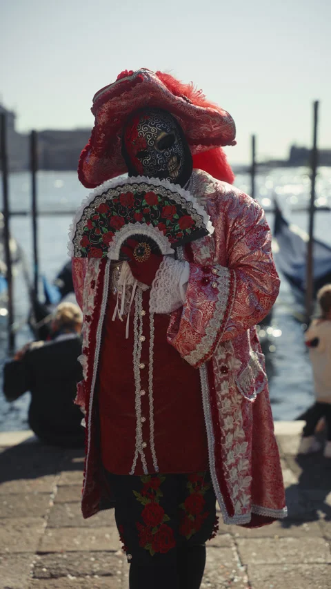 Portrait of performer in red medieval costume holds fan on Venice embankment Stock Footage 320108948