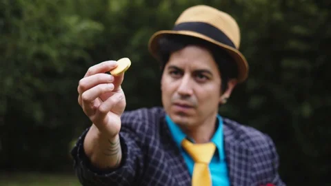 Portrait of a performing a magic trick by tossing a golden coin in his fingers Video stock 113938039