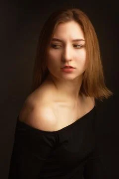 Portrait in the photo Studio of a brown-haired girl, on a black background in Stock Photos
