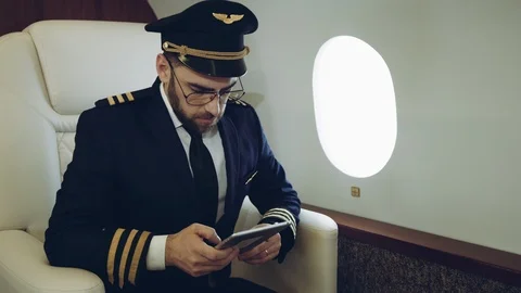 Portrait of pilot using the tablet, while waiting the flight inside the private Stock Footage 111066211