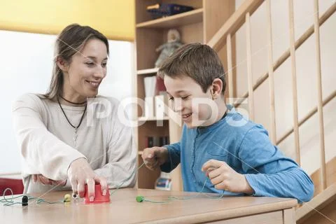 Portrait of playing boy and female childcare assistant Stock Photos