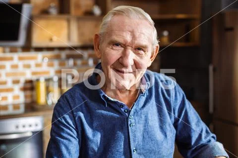 Portrait of pleasant aged man standing in the kitchen Stock Photos