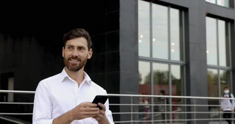 Portrait of pleasant bearded guy in white shirt walking near office center with Stock Footage 140684624