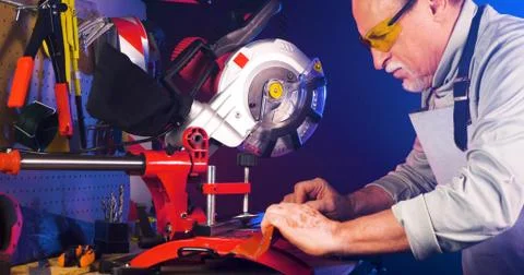 Portrait of pleasing old man working in modern industrial workshop. Stock Photos