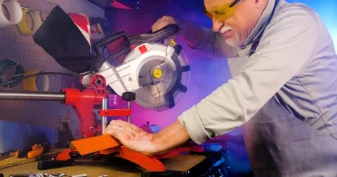 Portrait of pleasing old man working in modern industrial workshop. Stock Photos