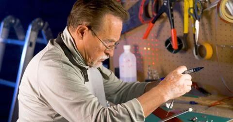 Portrait of pleasing old man working in modern industrial workshop. Stock Photos