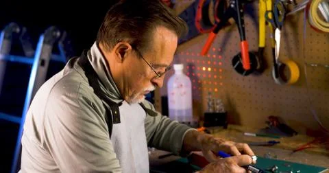Portrait of pleasing old man working in modern industrial workshop. Stock Photos