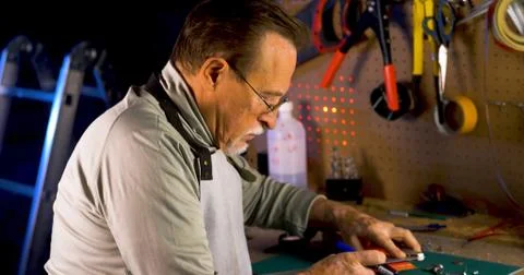 Portrait of pleasing old man working in modern industrial workshop. Stock Photos