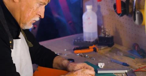 Portrait of pleasing old man working in modern industrial workshop. Stock Photos