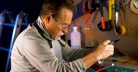 Portrait of pleasing old man working in modern industrial workshop. Stock Photos