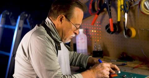 Portrait of pleasing old man working in modern industrial workshop. Stock Photos