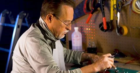 Portrait of pleasing old man working in modern industrial workshop. Stock Photos