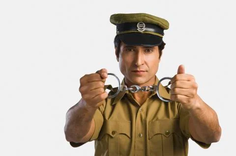 Portrait of a policeman holding a pair of handcuffs Stock Photos