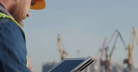 A Portrait Port Worker With A Beard In A Yellow Helmet, Works With A Tablet Stock Footage 121660679