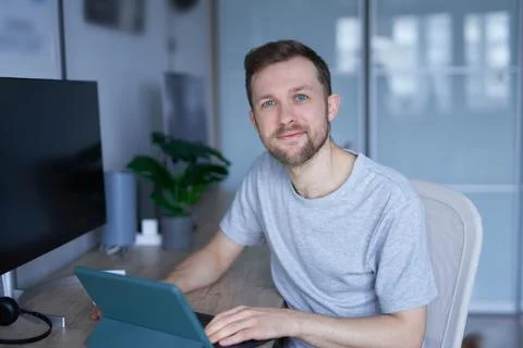 Portrait of positive freelancer using tablet device to learn or work online 库存照片