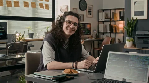 Portrait of Positive Long-Haired Gen Z Programmer at Wooden Desk in IT Office Stock-Footage 329613974