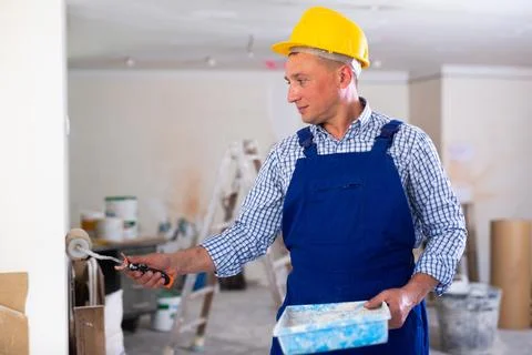 Portrait of positive man painter in a protective helmet and overal with paint Stock Photos