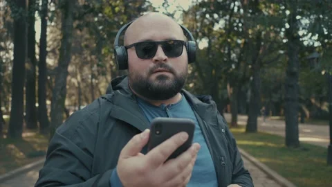 Portrait of positive plus-size man in headphones enjoying listening to music on Stock Footage 231919554