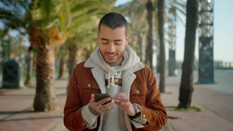 Portrait of positive young Hispanic man holding black mobile device at palm Stock Footage 136673852
