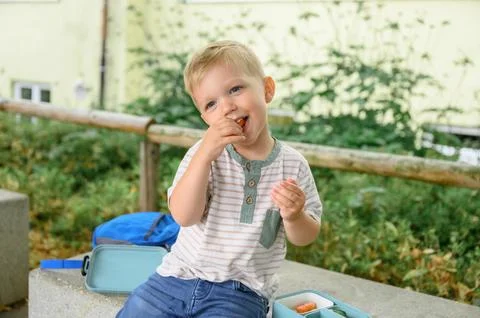 Portrait of a pre schoolboy with a backpack, a boy eating fruits after school. Stock Photos