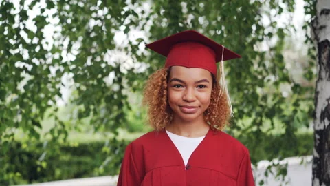 Portrait of pretty African American girl graduating student in red gown and Stock Footage