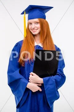 Portrait of pretty cheerful girl in gown and graduation cap Stock Photos