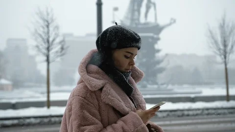 Portrait of pretty girl using mobile device at snowfall. Big town or city street Stock Footage 105995571