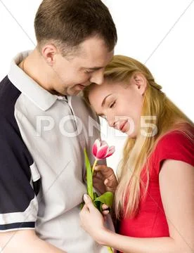 Portrait of pretty woman holding tulip in hand and looking at it with kind man n Stock Photos
