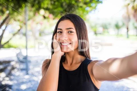Portrait of pretty young latin girl taking selfies with her smart phone in th Stock Photos