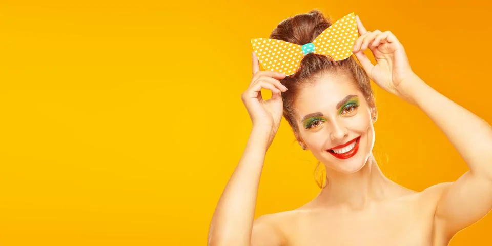 Portrait of an pretty young woman posing in paper bow in pin-up style on a ye Stock Photos