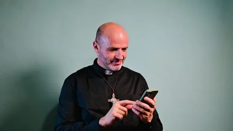 Portrait of a priest with crucifix using a smartphone. Stock Footage 258943742
