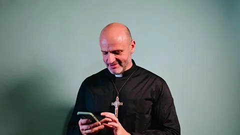 Portrait of a priest with crucifix using a smartphone. Stock-Footage 258943762