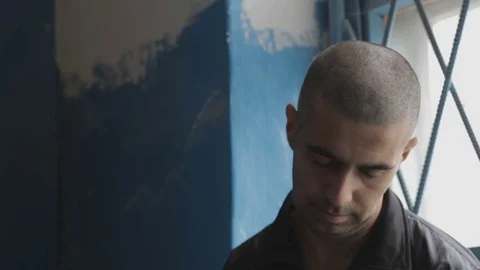 Portrait of a prisoner sitting at the window frame Video stock 73619596