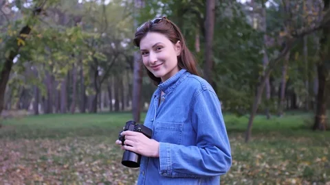 Portrait of a professional freelancer with a camera in hand in the autumn forest Stock Footage 124554062